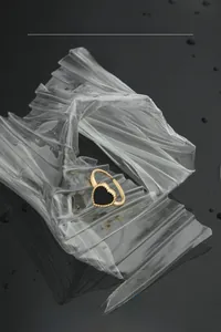 Macro detail of black heart ring with gold beaded edge on a modern reflective surface