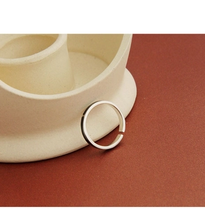 Macro shot of minimalist S925 sterling silver open ring on white ceramic edge