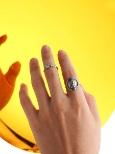 Detail of vintage coin relief ring and minimalist silver band with clear gemstone