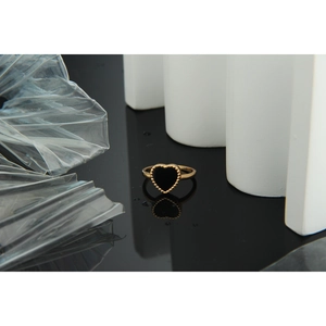 Detailed macro view of black heart ring with gold beaded edge on glossy surface
