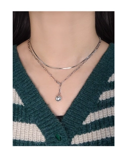 Detail of layered silver snake chain and paperclip link necklace with a polished bead pendant
