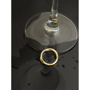 Vue détaillée d'une bague Mobius dorée avec zircons pavés sur un miroir noir poli