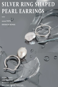 Detail of silver hoop earrings with irregular baroque pearl on reflective surface