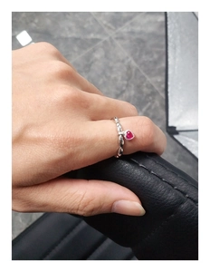 Macro shot of silver heart ring with red gemstone and beaded texture band