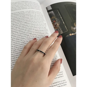 Minimalist S925 sterling silver ring with black enamel band shown on a hand over a book