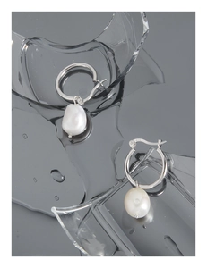 Detail of S925 sterling silver hoop earrings with baroque pearls on glass background