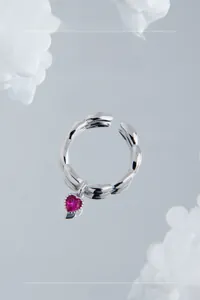 Macro shot of silver wavy band ring featuring a pink heart-shaped zircon pendant