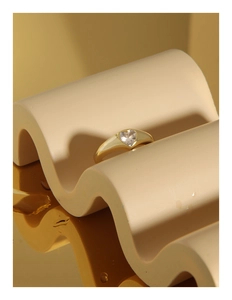 Macro shot of gold heart ring with zircon stone on elegant textured surface
