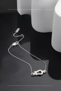 Detail of S925 silver horseshoe bracelet with pave stones on black mirror surface