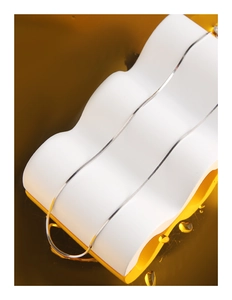 Macro shot of silver snake chain on white wave stand with amber water background