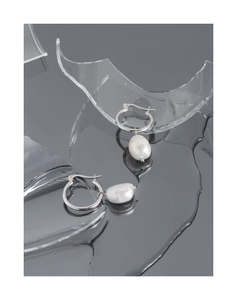 Detail of S925 silver earrings with baroque pearls on a sleek mirror water surface