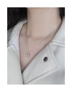 Gros plan d'un collier minimaliste en argent avec petite fleur porté par un mannequin