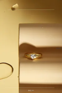 Detailed view of a wide gold band ring featuring a heart-shaped cubic zirconia stone