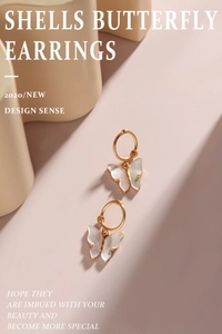 Macro detail of gold butterfly earrings with pearlescent shell texture on a pink background