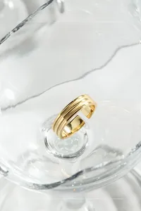Vue détaillée d'une bague minimaliste dorée dans un récipient en verre cristal