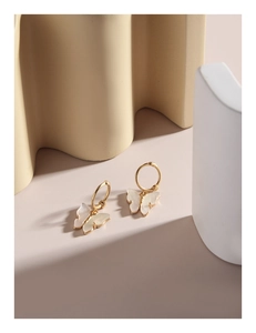 Detail of golden butterfly earrings with iridescent shell inlay on wave texture base