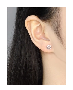Close-up of minimalist silver smiley face stud earring worn on a model ear