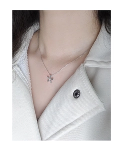 Gros plan d'un collier en argent 925 avec pendentif fleur porté sur le cou d'un modèle