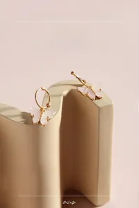 Detailed view of 925 silver butterfly earrings with shell inlay on beige geometric stand
