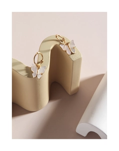 Close-up of elegant gold butterfly stud earrings with pearlescent shell inlay