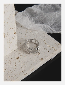 Detail of multi-layer silver open ring with round beads on elegant travertine stone