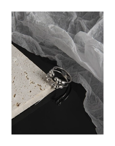 Detailed view of an irregular molten silver ring on a textured travertine stone base