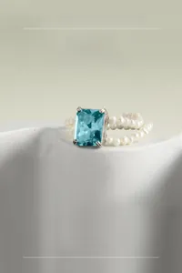 Detail of S925 silver ring with blue gemstone and white pearl woven band on stone