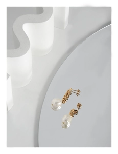 Détail macro d'une boucle d'oreille chaîne en perle asymétrique avec finition dorée