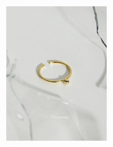 Détail d'une bille en or 18 carats sur une bague fine ouverte en argent S925 poli