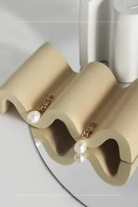 Détail de boucles d'oreilles perles asymétriques sur un support céramique moderne