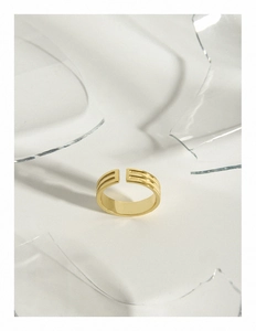 Vue détaillée d'une bague dorée réglable avec rainures parallèles sur fond de verre brisé