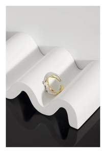 Macro di anello a onde bicolore con piccola perla su un supporto geometrico bianco puro
