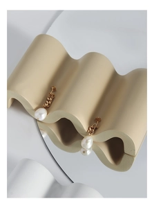 Détail de boucles d'oreilles perles baroques et chaîne dorée sur support en céramique