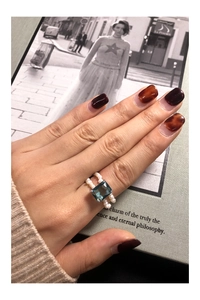 Detailed view of rectangle blue zircon ring with double rows of white pearls on hand