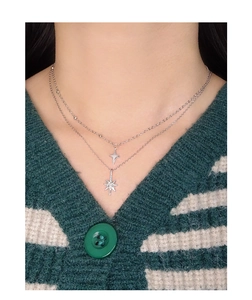 Detail of layered S925 silver necklace featuring starburst pendants on a female model