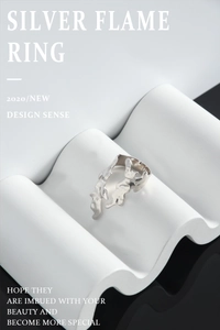 Macro shot of silver flame ring with textured molten lava design on white wavy art stand