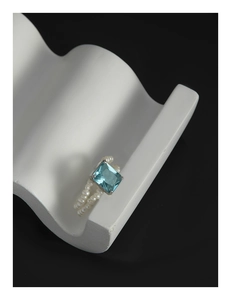 Macro shot of silver ring featuring emerald-cut blue zircon and white pearl band detail