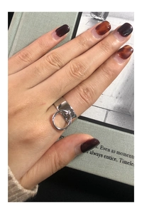 Macro shot of wide silver ring with a dangling solid metal circle on hand