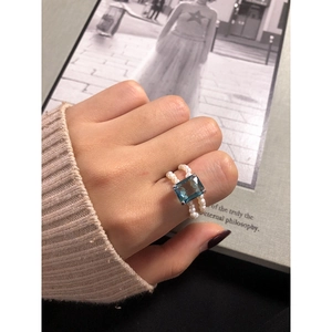 S925 silver ring with rectangular blue zircon and double-row white pearls on art background