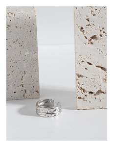 Macro detail of irregular lava texture on s925 silver open ring with stone backdrop