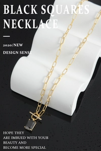 Detailed view of square black gemstone pendant with OT buckle on a gold link chain