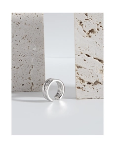 Macro shot of silver ear cuff with irregular hammered texture on stone background