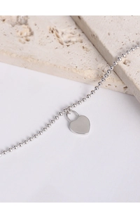 Detailed macro view of S925 sterling silver beaded chain with polished heart lock pendant