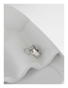 Detailed close-up of wide polished silver band with a dangling ring on art pedestal