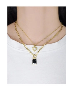 Detail of layered gold necklaces with black gemstone pendant and paperclip chain style