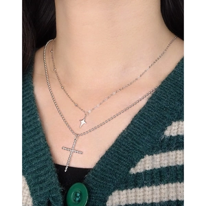 Double layer S925 sterling silver star and cross necklace worn on a striped sweater