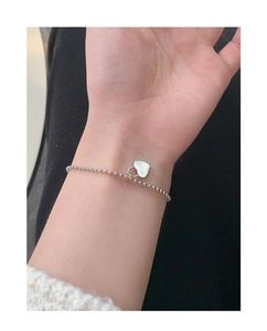 Detail of S925 sterling silver beaded bracelet with heart charm on female wrist