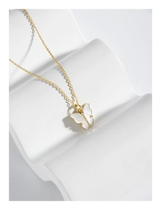Vue détaillée du pendentif papillon doré avec incrustation en nacre blanche