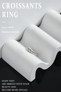 Macro detail of silver croissant ring showing twisted texture on white podium