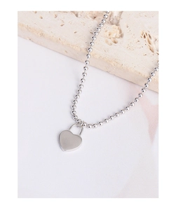 Macro detail of polished heart lock pendant on a silver-toned beaded bracelet